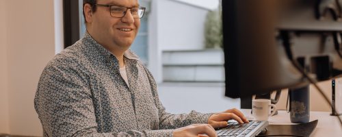 Man achter bureau werkt op computer met toetsenbord en muis in moderne kantooromgeving