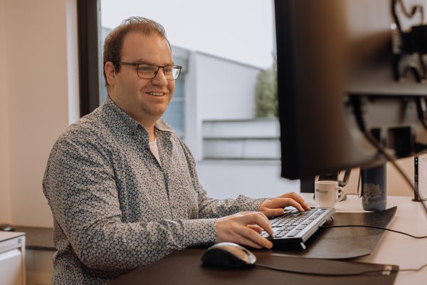 Man achter bureau werkt op computer met toetsenbord en muis in moderne kantooromgeving